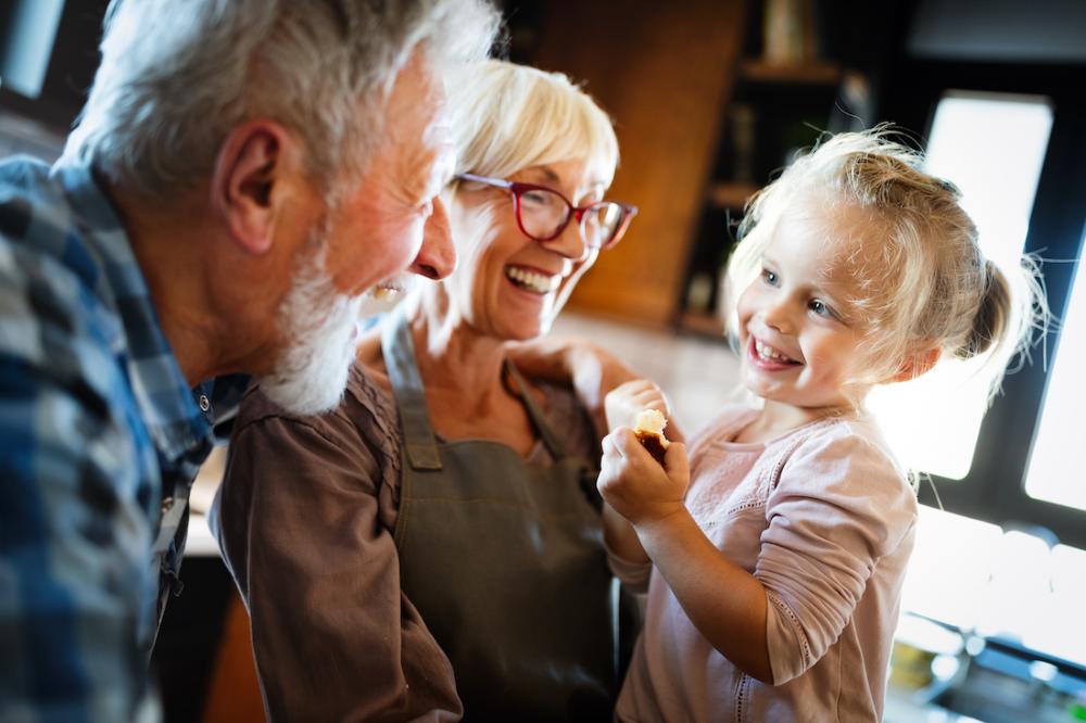 An older couple laughing with their granddaughter