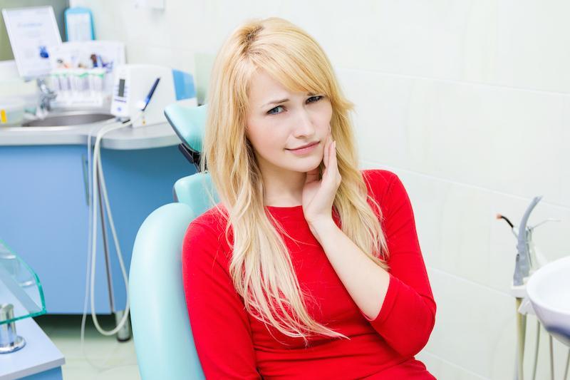 woman holding her jaw with concern on a dental chair in jensen beach fl