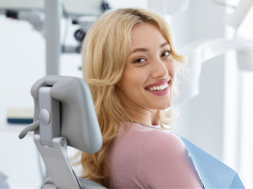 Relaxed, smiling patient in dental chair wearing bib, comfortable with oral sedation dentistry